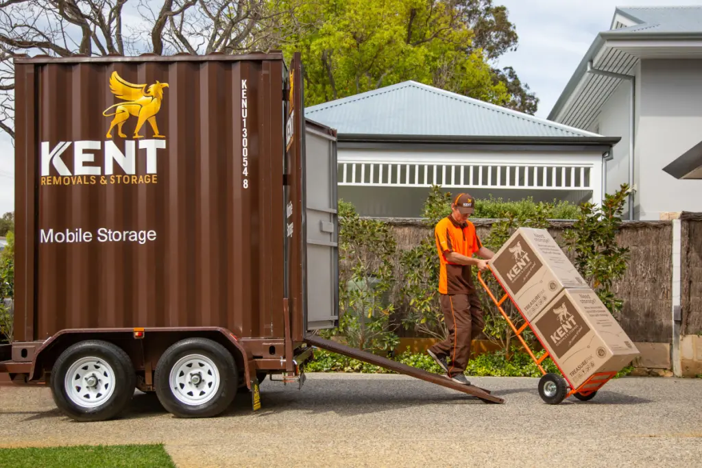 Kent Removals worker unloading boxes from mobile storage container using a trolley