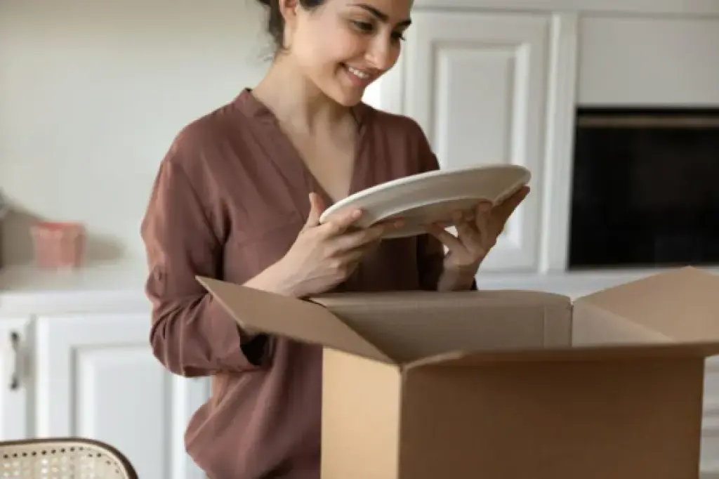 Woman unpacking fragile plate from moving box after relocation
