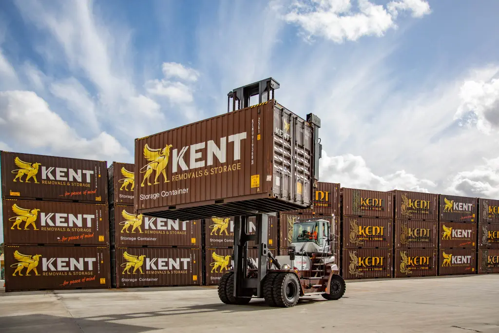 Professional container storage yard with a heavy-duty forklift safely lifting a secure Kent Removals and Storage container