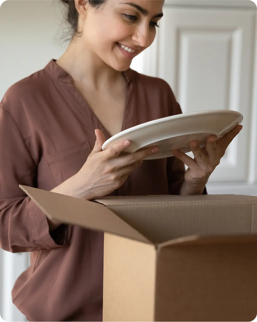 Woman unpacking fragile plate from moving box after relocation