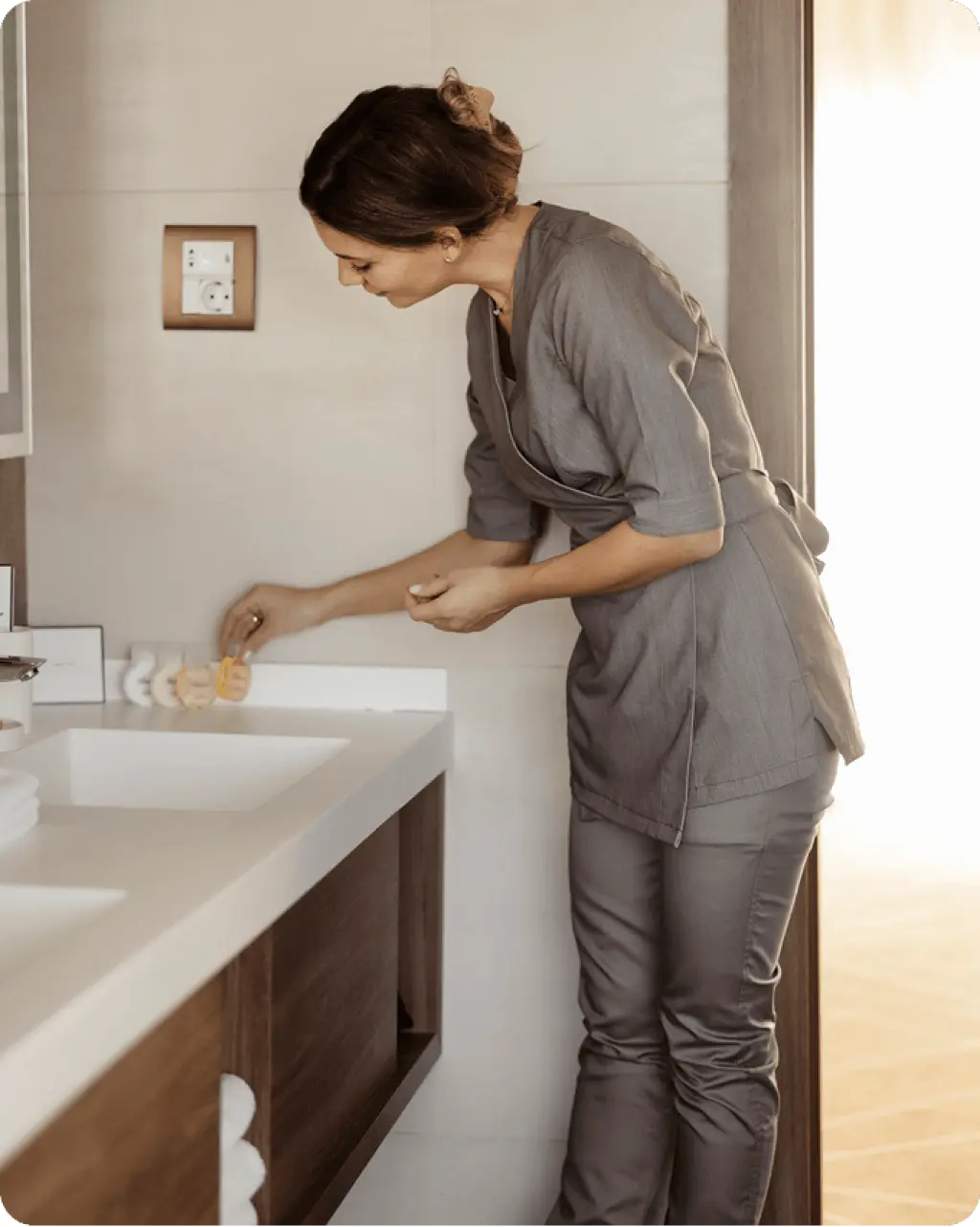 Housekeeper arranging toiletries on bathroom vanity counter