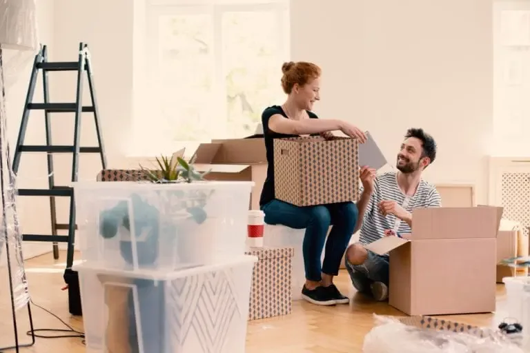 Smiling couple unpacking boxes together during house move