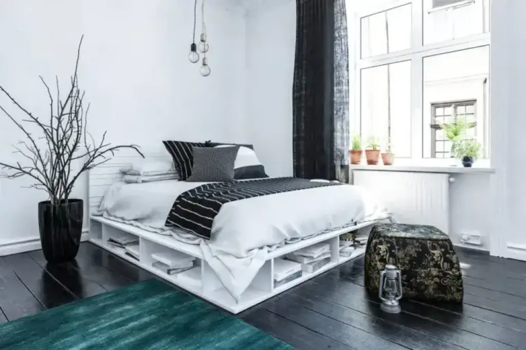 Modern Scandinavian bedroom with white pallet bed frame and dark wood floor