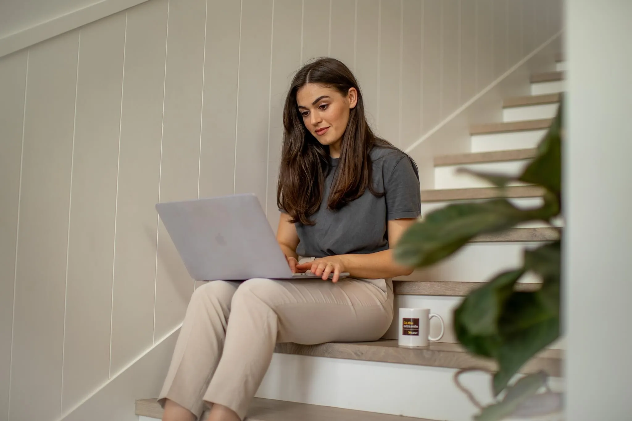 Woman using laptop at home stairs planning relocation and storage with Kent Removals & Storage