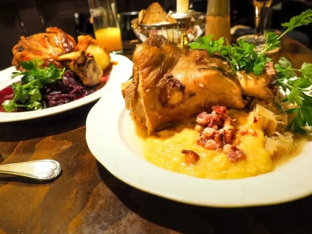 Roasted pork knuckle served with polenta and sauerkraut on a dinner table