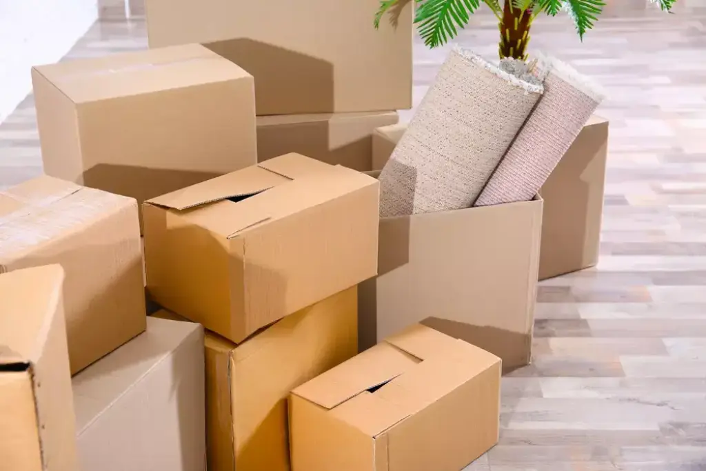 Stacked moving boxes with rolled rugs indoors
