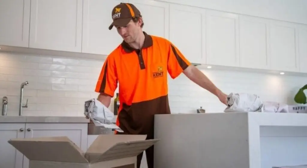 Kent Removals staff member unpacking kitchenware from box in white kitchen