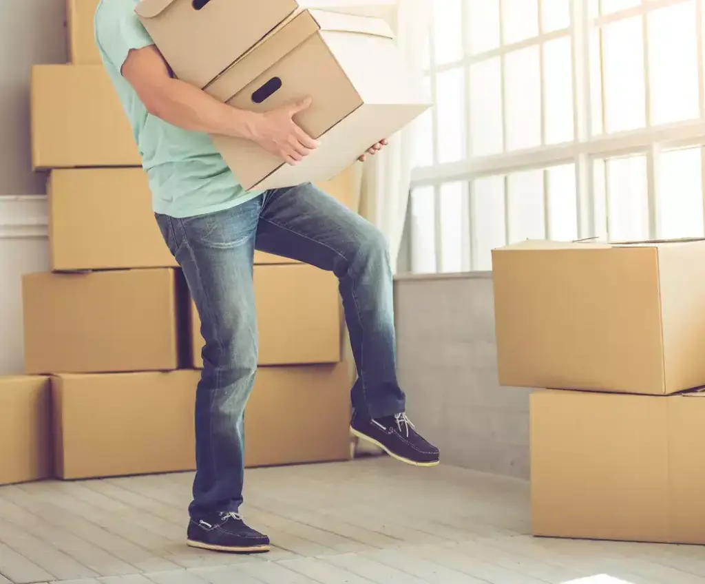 Man carrying moving boxes inside house