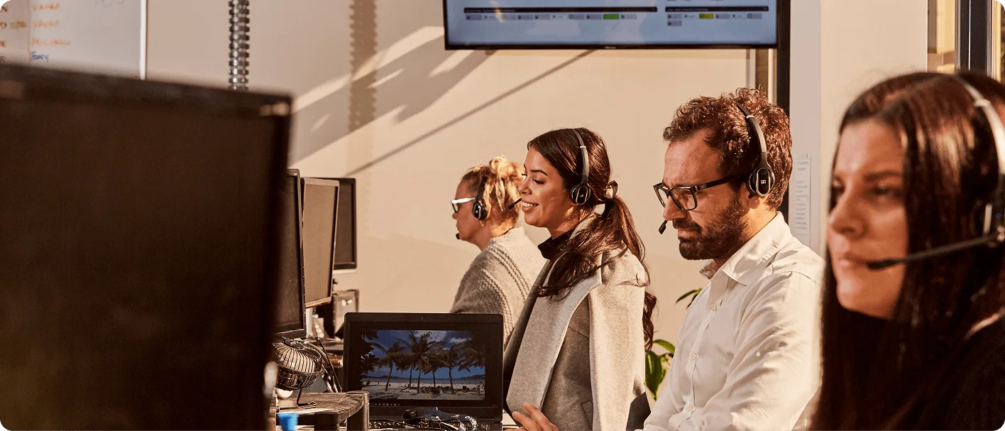 Customer service team wearing headsets working at computers in a modern office call center.