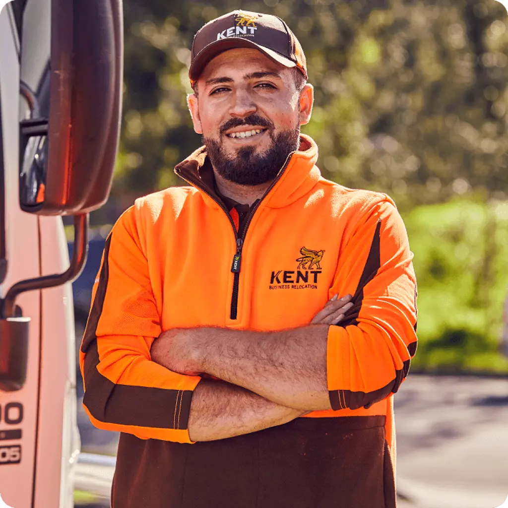 Smiling Kent Business Relocation staff member in orange uniform standing by truck