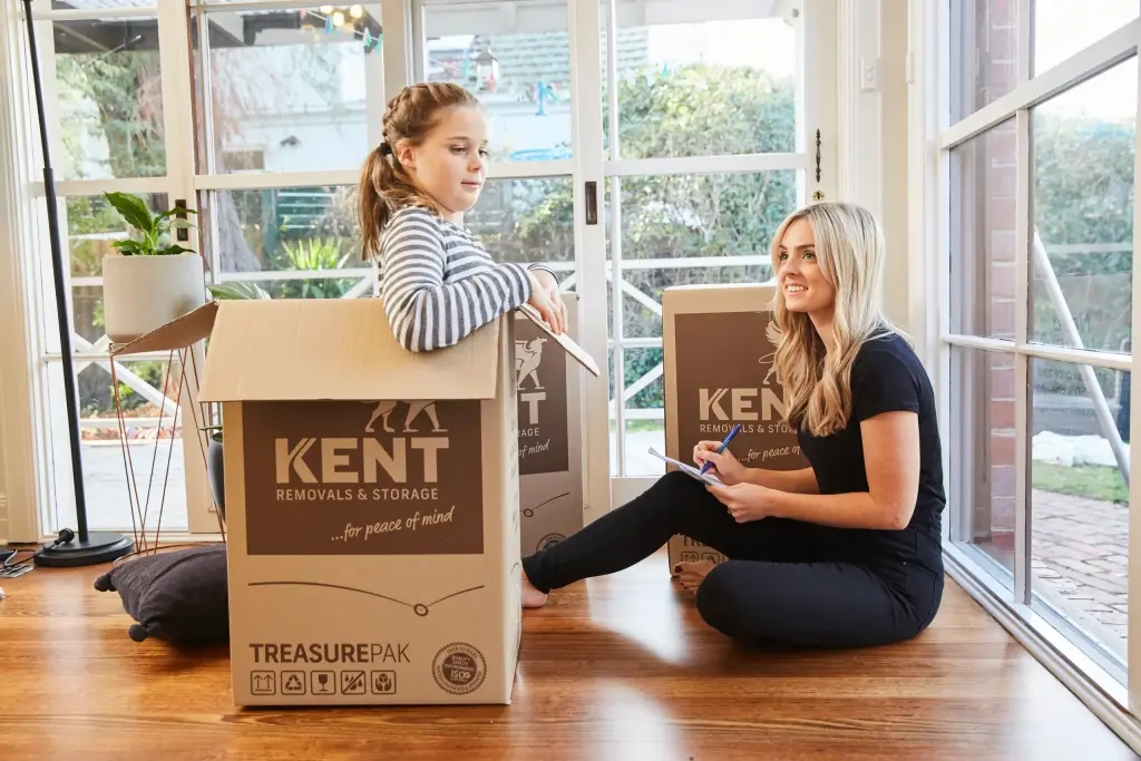 Woman and child sitting with Kent Removals TreasurePak moving boxes indoors