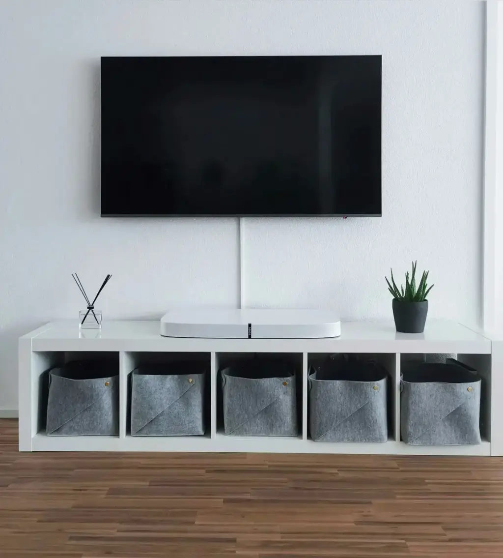 Minimalist living room with wall-mounted TV and white storage unit with fabric bins