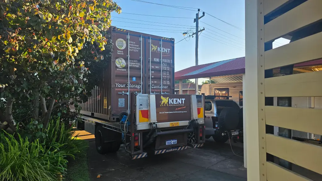 Kent Removals truck delivering storage container to residential property driveway
